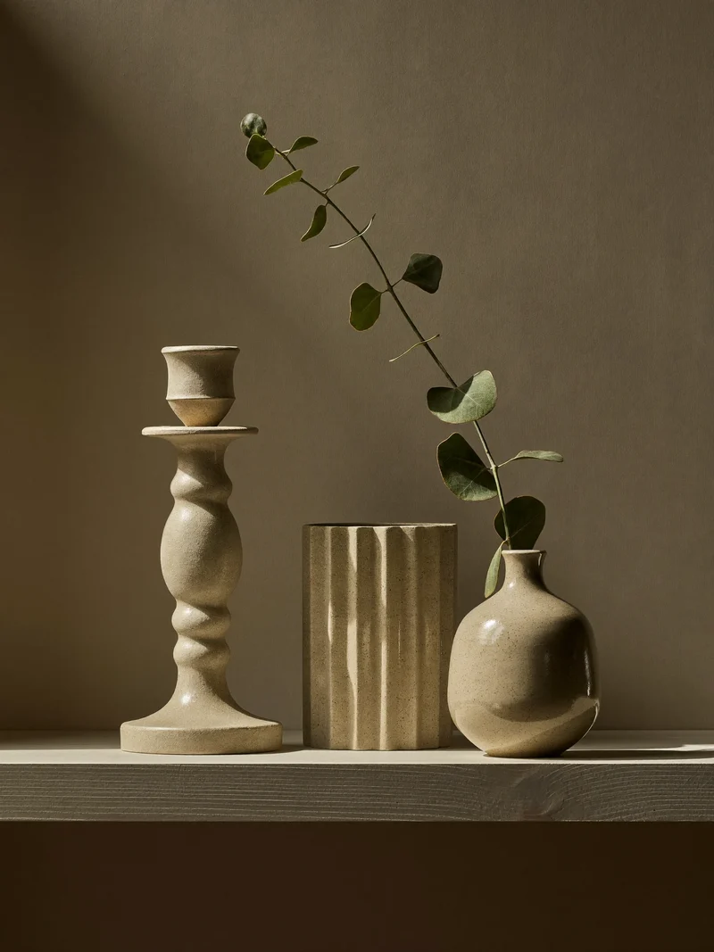 Steingut-Kerzenhalter und kleine Vase mit einem einzelnen Eukalyptuszweig im Regal